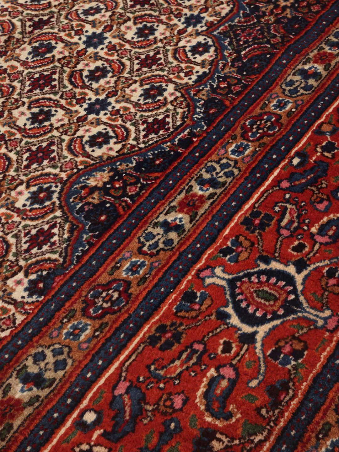 A hand-knotted Moud rug from the Middle East in dark-red and blue tones.