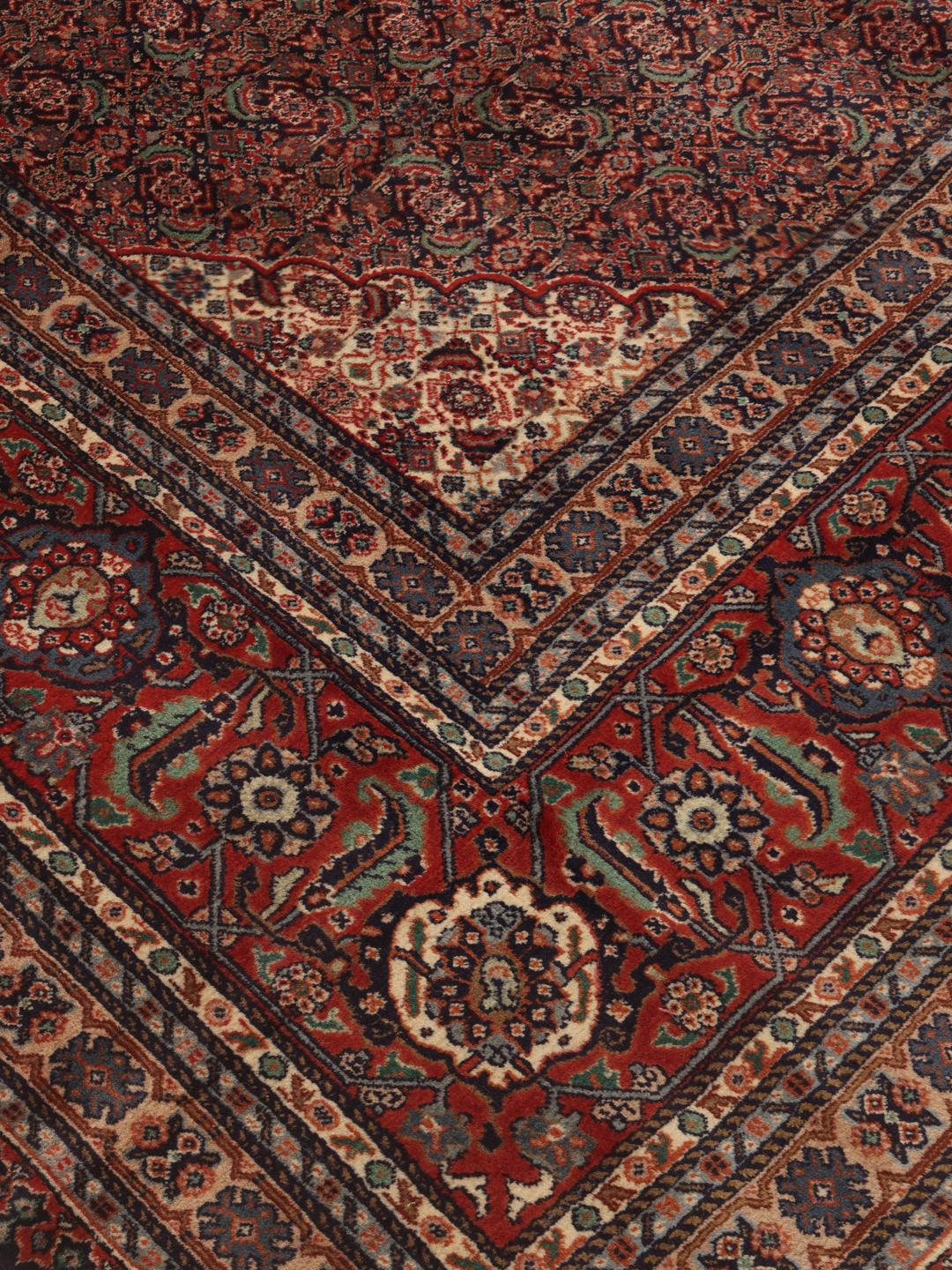 A large Moud rug from the Middle East featuring a dark-red field with a central medallion.