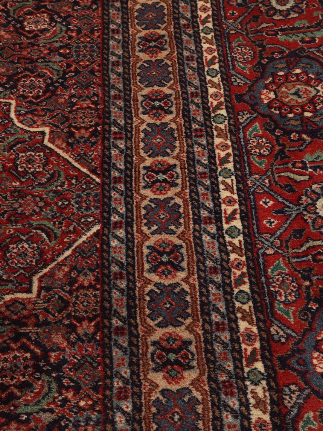A large Moud rug from the Middle East featuring a dark-red field with a central medallion.