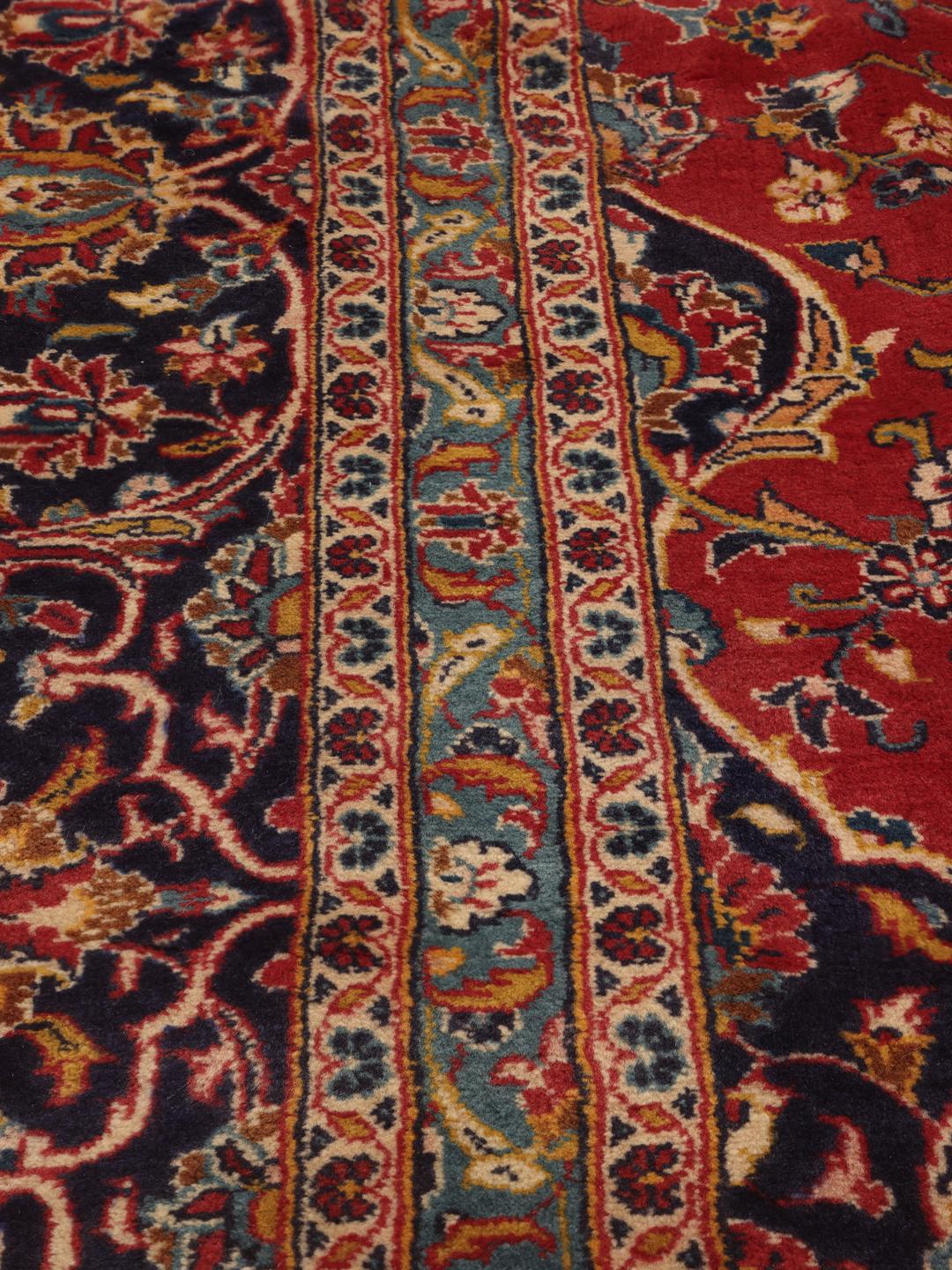 Handgeknoopt Keshan tapijt uit het Midden-Oosten met een levendig rood en donkerblauw bloemmotief.