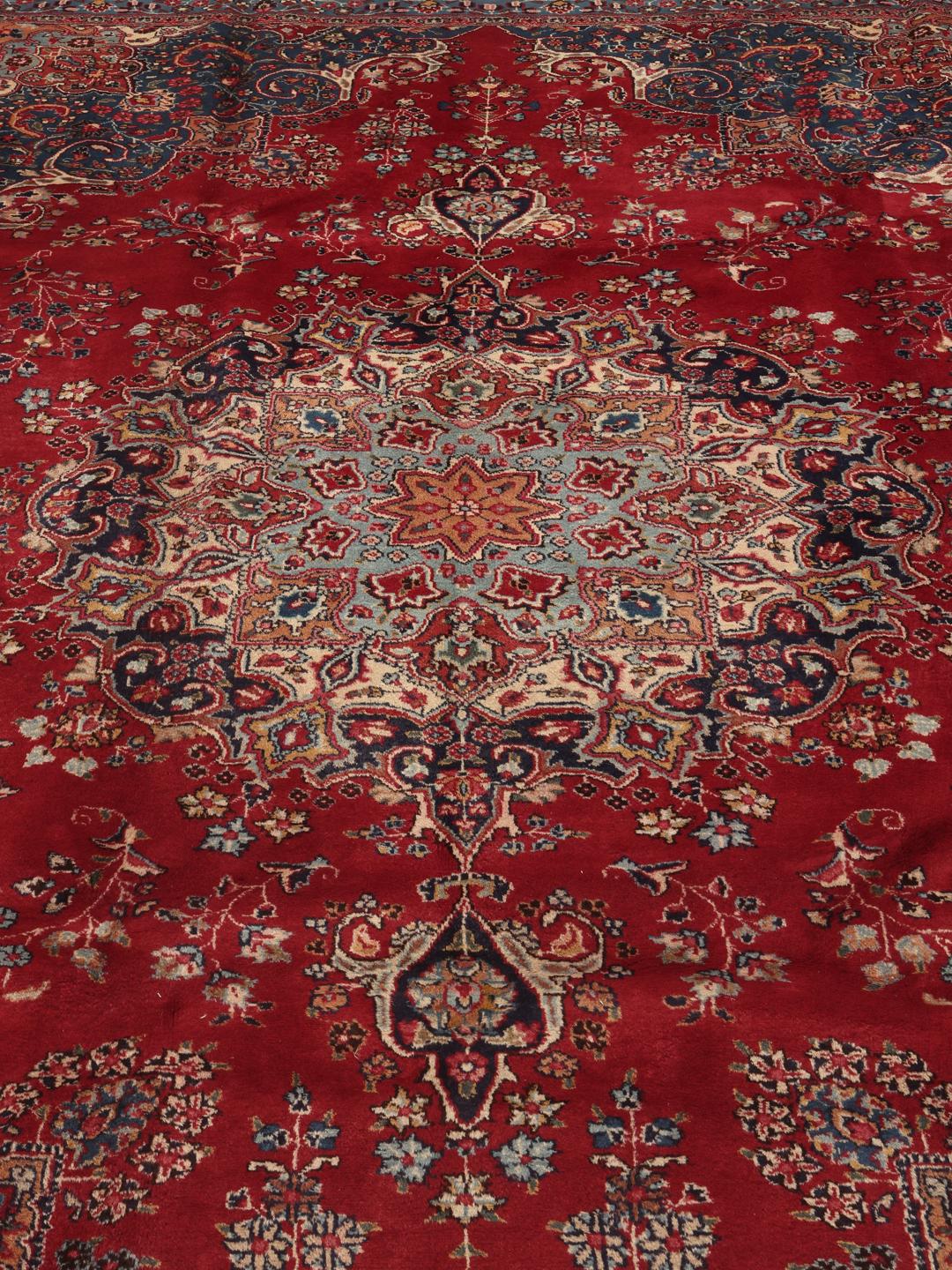 A hand-knotted Mashad rug from the Middle East in deep red and blue tones.