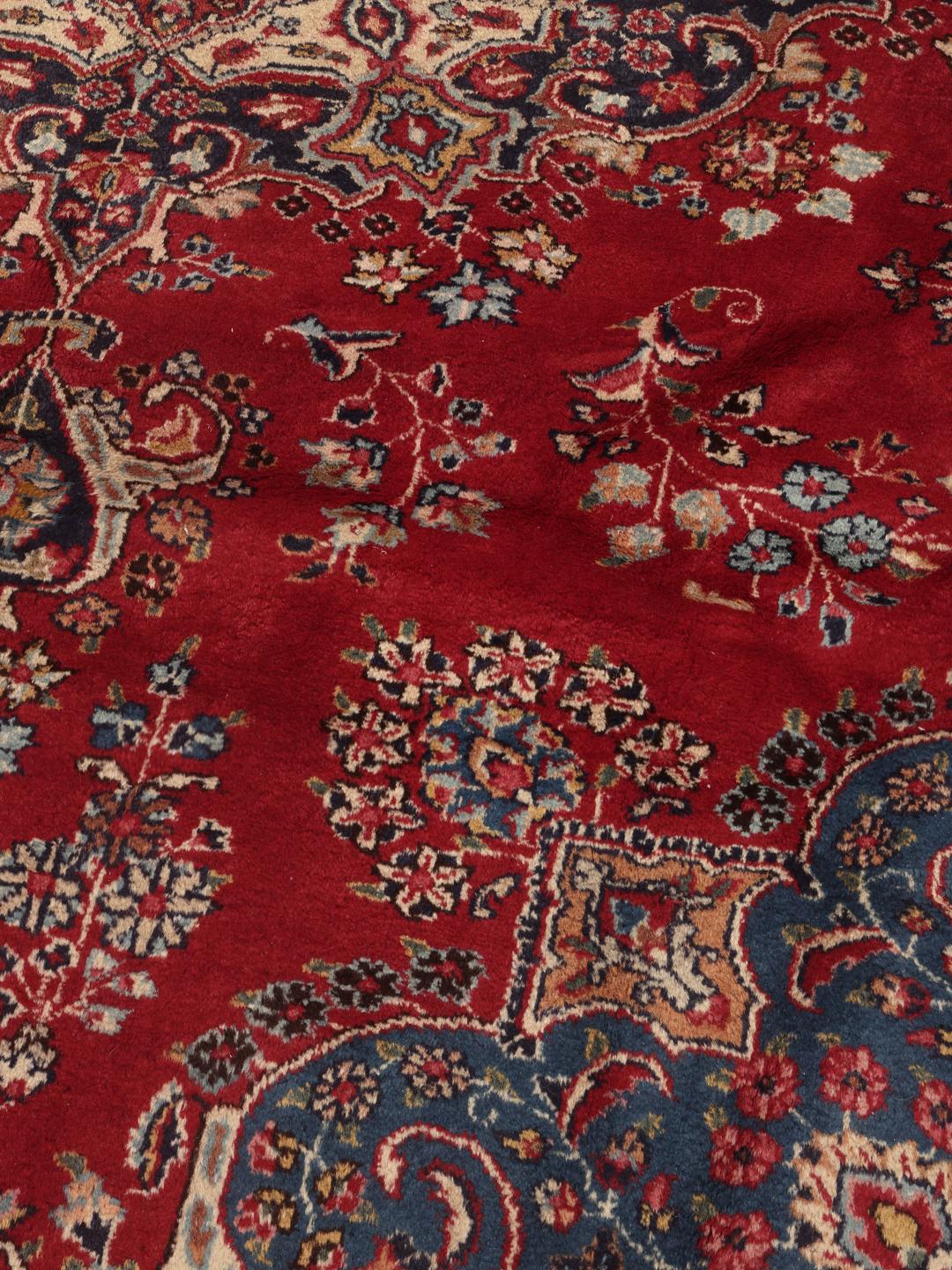 A hand-knotted Mashad rug from the Middle East in deep red and blue tones.