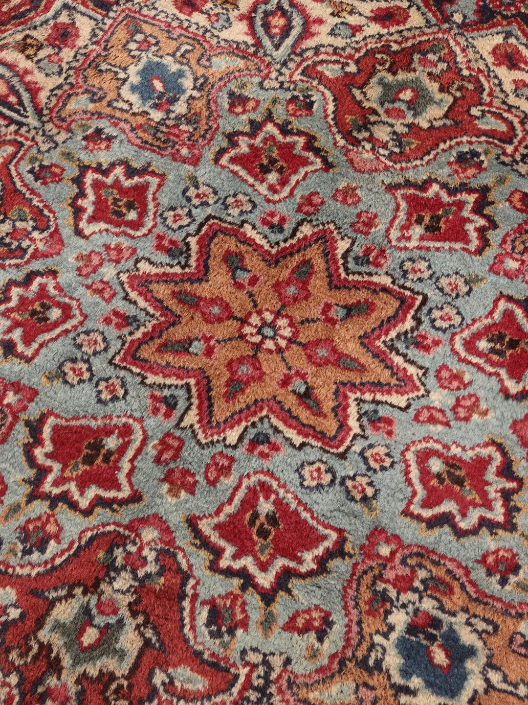 A hand-knotted Mashad rug from the Middle East in deep red and blue tones.