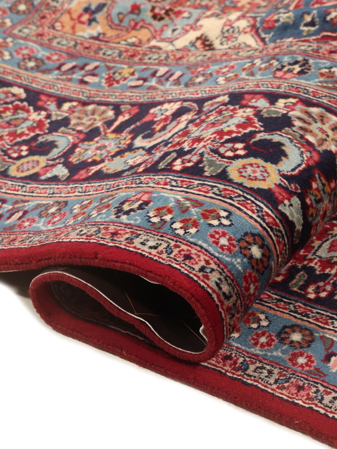A hand-knotted Mashad rug from the Middle East in deep red and blue tones.
