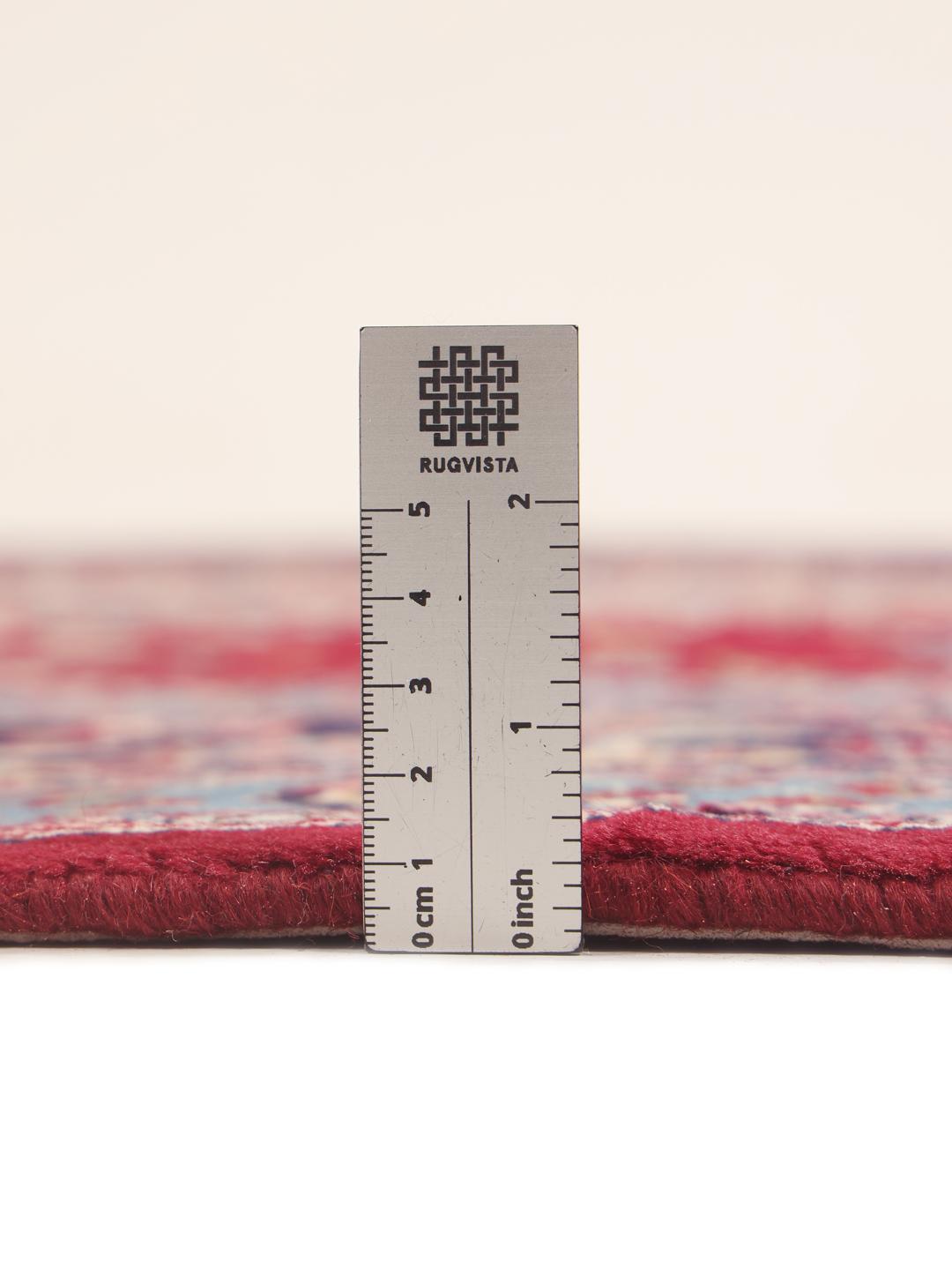 A hand-knotted Mashad rug from the Middle East in deep red and blue tones.