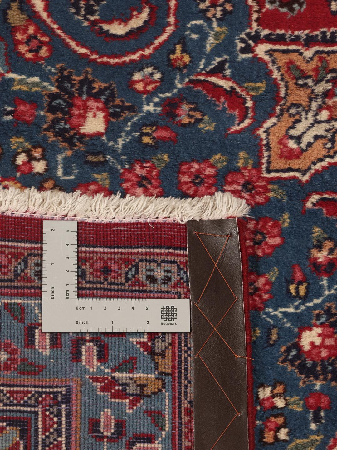 A hand-knotted Mashad rug from the Middle East in deep red and blue tones.