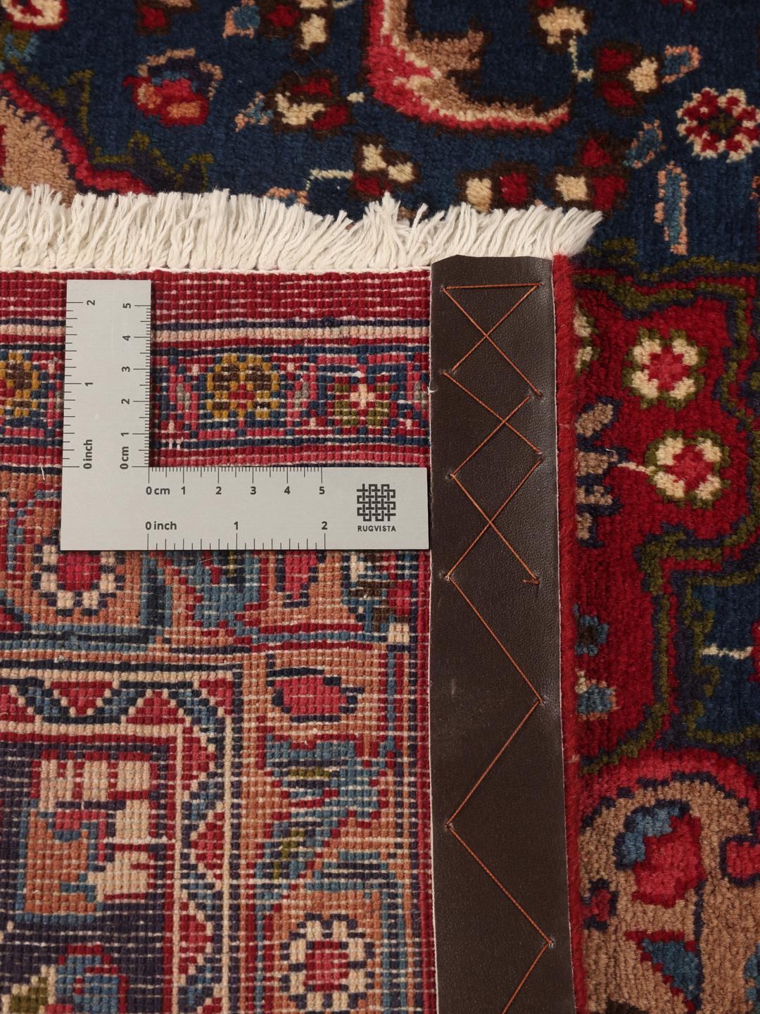 Et håndknyttet Mashad-tæppe fra Mellemøsten med et dybrødt felt og dekorative blå blomstermønstre.