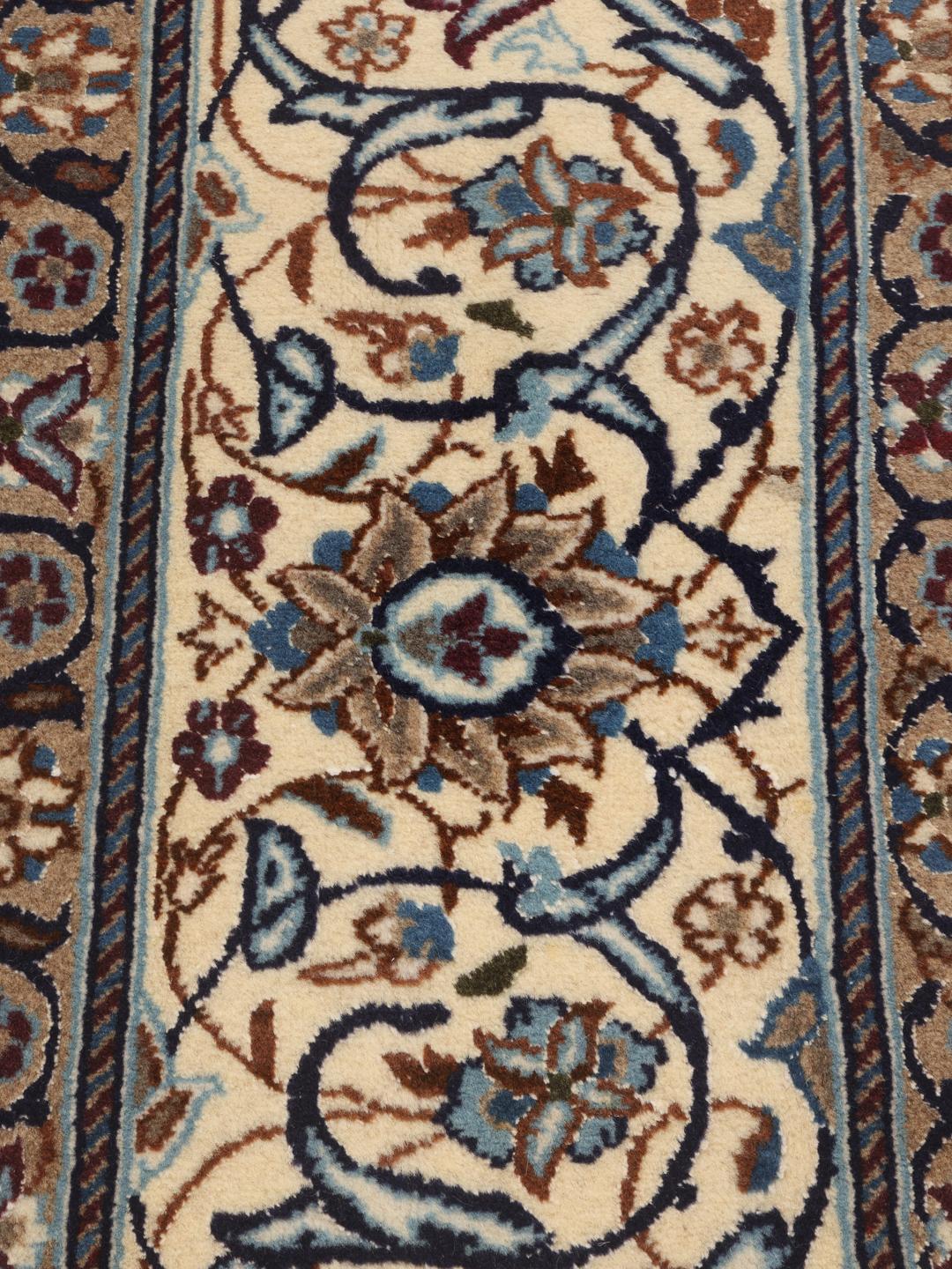 A rectangular Nain rug from the Middle East featuring a floral pattern in beige and blue.