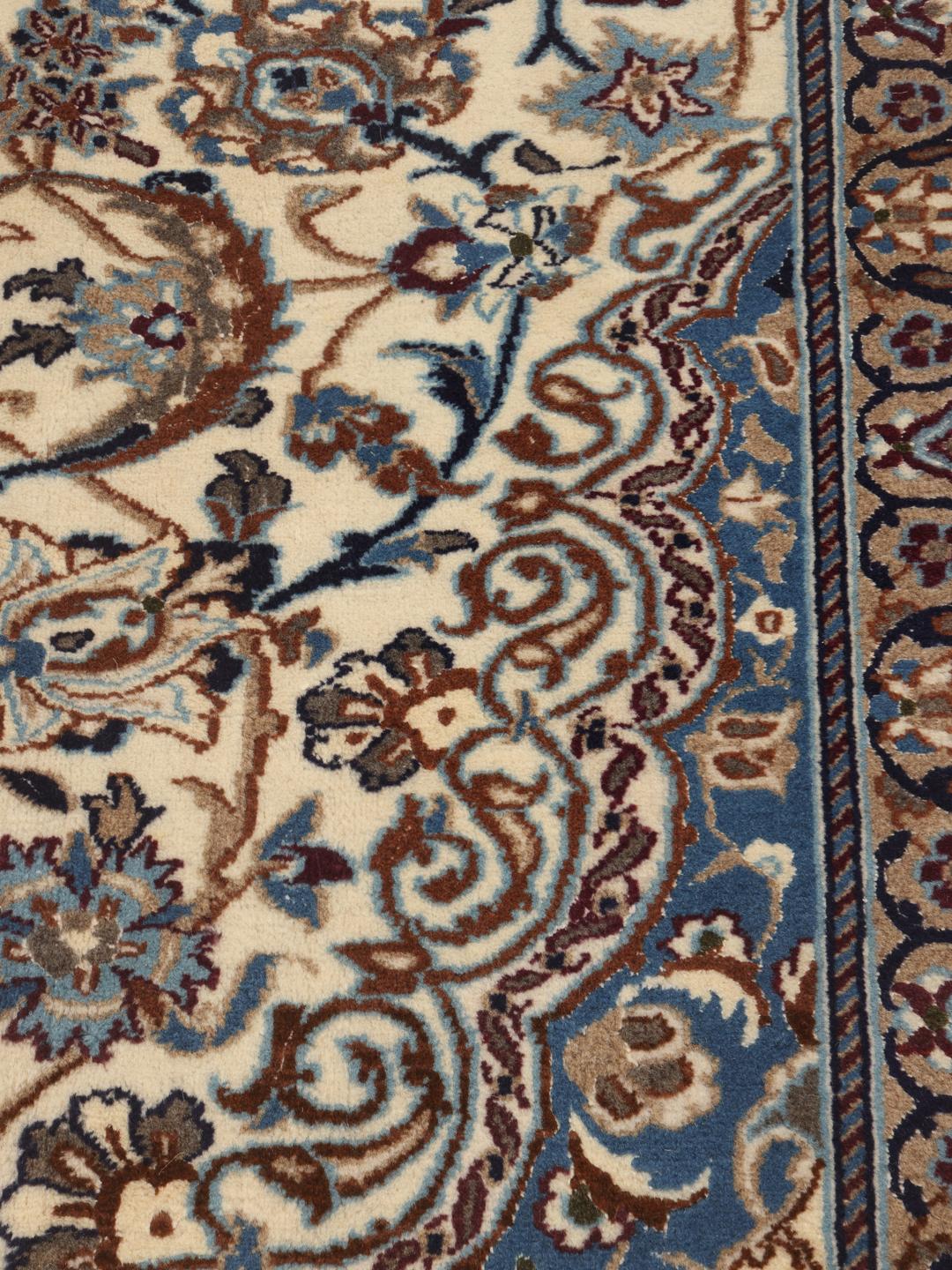 A rectangular Nain rug from the Middle East featuring a floral pattern in beige and blue.