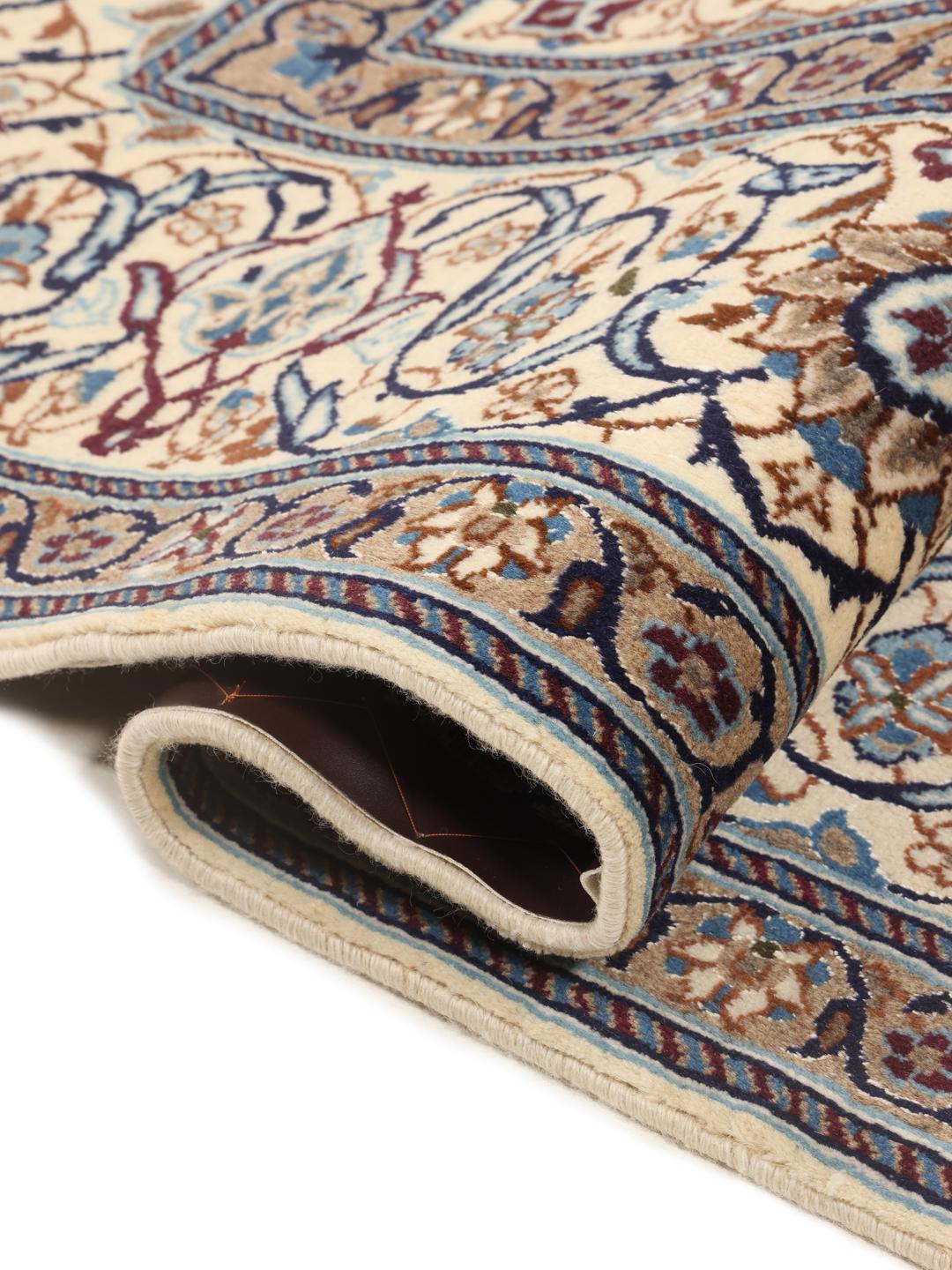 A rectangular Nain rug from the Middle East featuring a floral pattern in beige and blue.