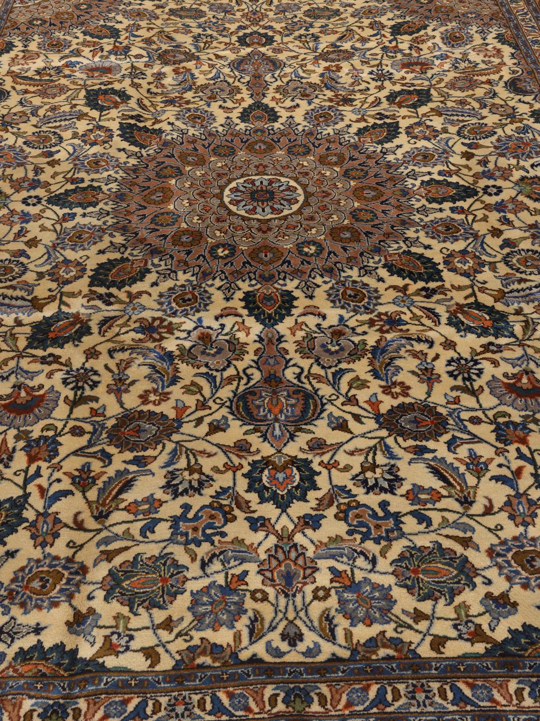 Een handgeknoopt Kashmar-tapijt uit het Midden-Oosten met een centraal medaillon en bloemmotieven in bruin, blauw en crème.