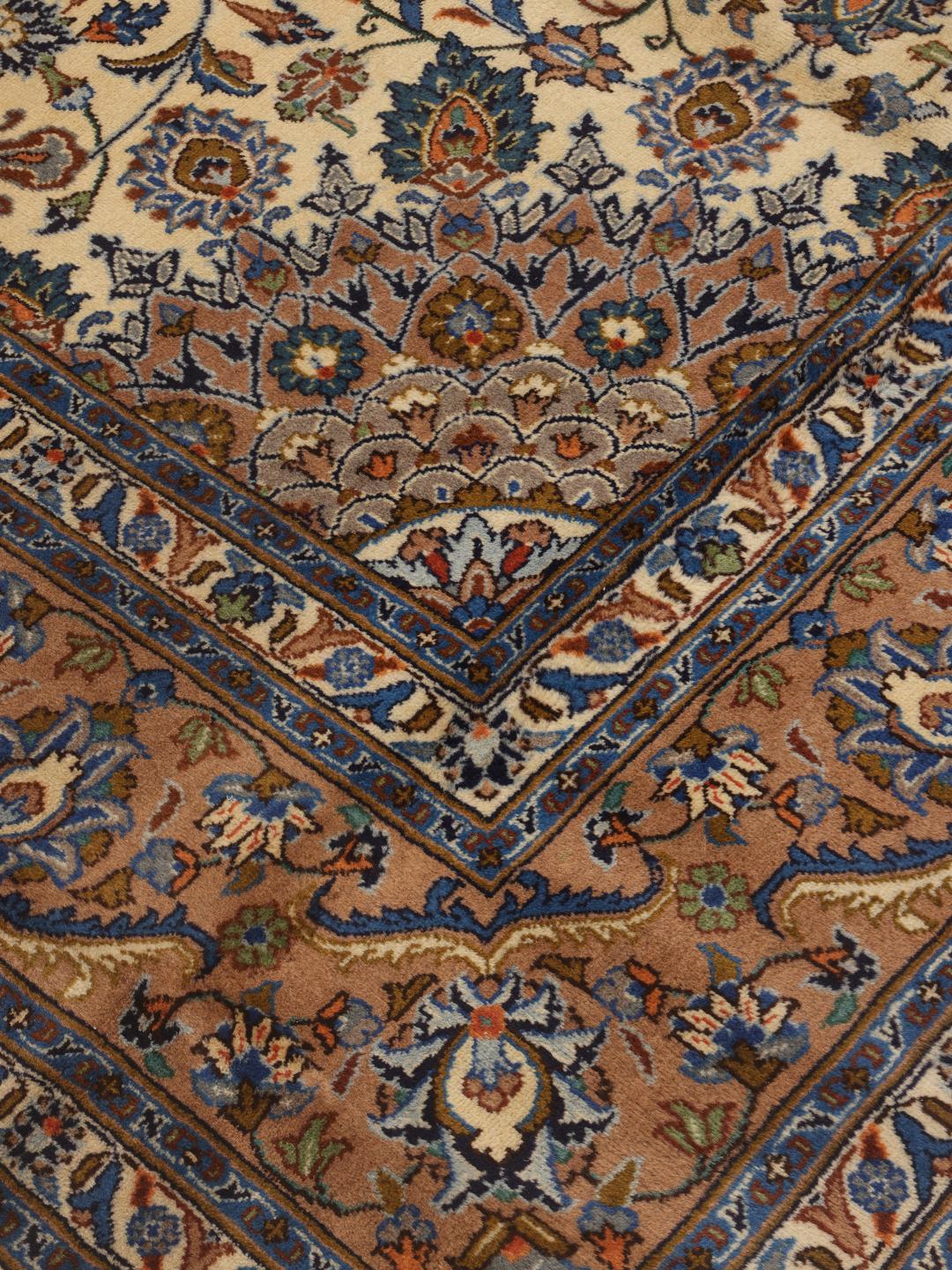 Een handgeknoopt Kashmar-tapijt uit het Midden-Oosten met een centraal medaillon en bloemmotieven in bruin, blauw en crème.