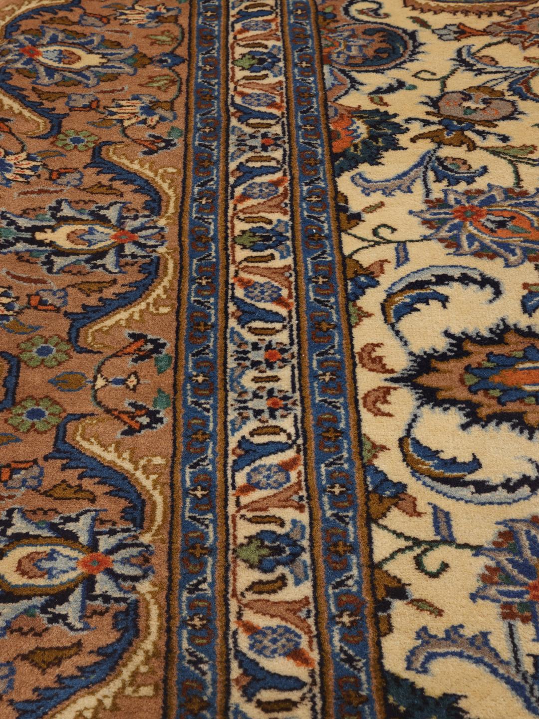 Een handgeknoopt Kashmar-tapijt uit het Midden-Oosten met een centraal medaillon en bloemmotieven in bruin, blauw en crème.