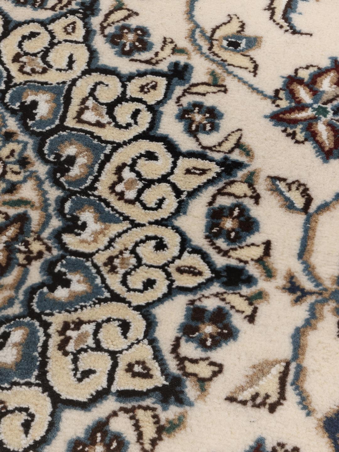 Een handgeknoopt Nain-tapijt uit het Midden-Oosten met een beige achtergrond en blauwe bloemmotieven
