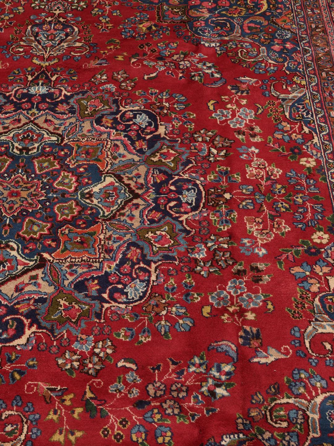 A hand-knotted Mashad rug from the Middle East in shades of red and blue.