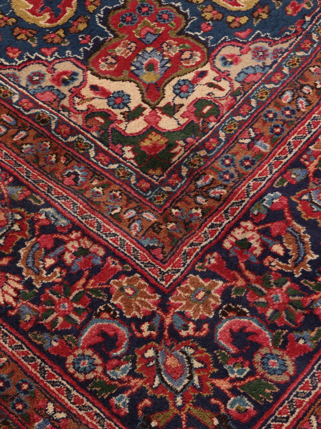A hand-knotted Mashad rug from the Middle East in shades of red and blue.