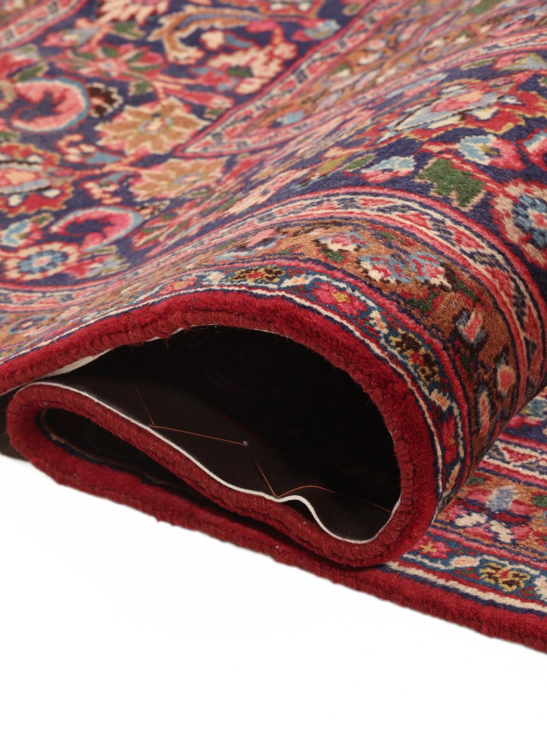 A hand-knotted Mashad rug from the Middle East in shades of red and blue.