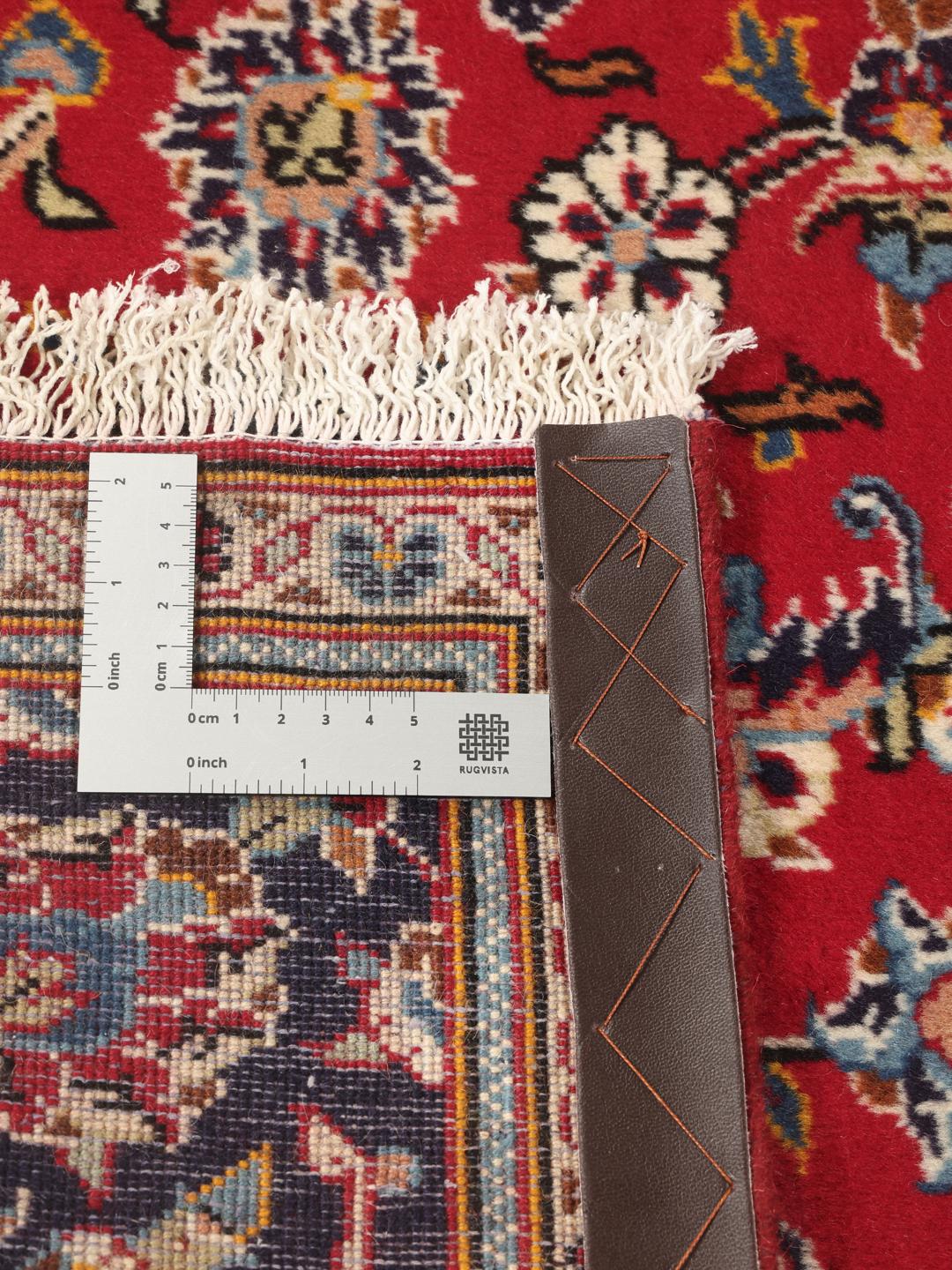A hand-knotted Middle Eastern Keshan rug with a red and blue floral medallion design.