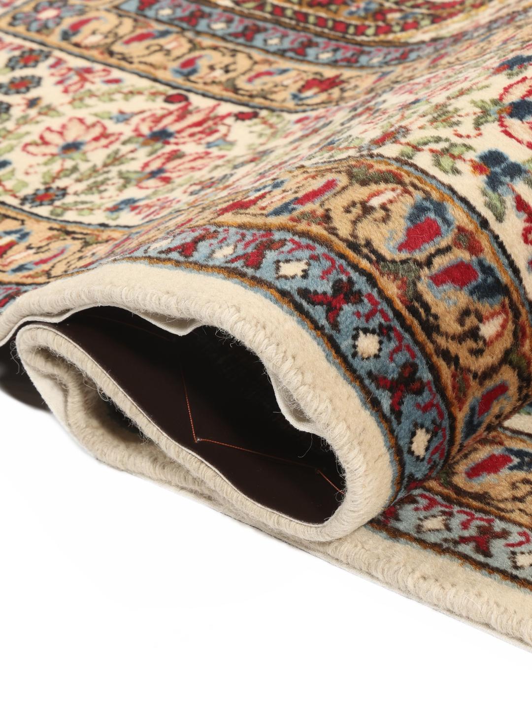 Een handgeknoopt Kerman tapijt uit het Midden-Oosten met een beige veld en rode en blauwe paisley-motieven.