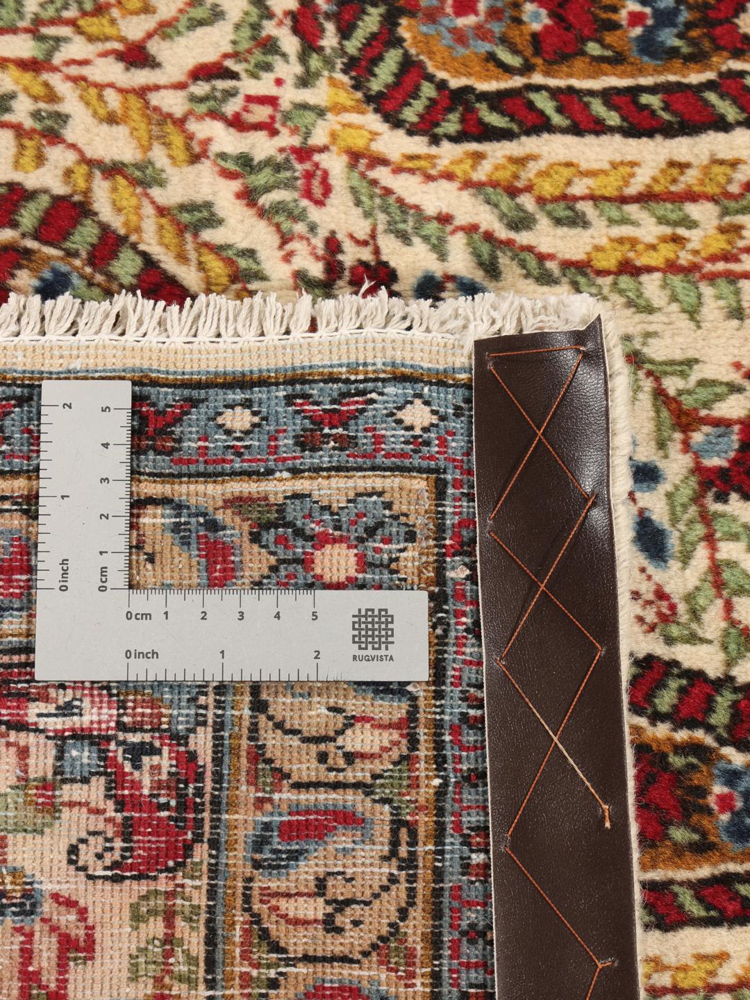 Een handgeknoopt Kerman tapijt uit het Midden-Oosten met een beige veld en rode en blauwe paisley-motieven.