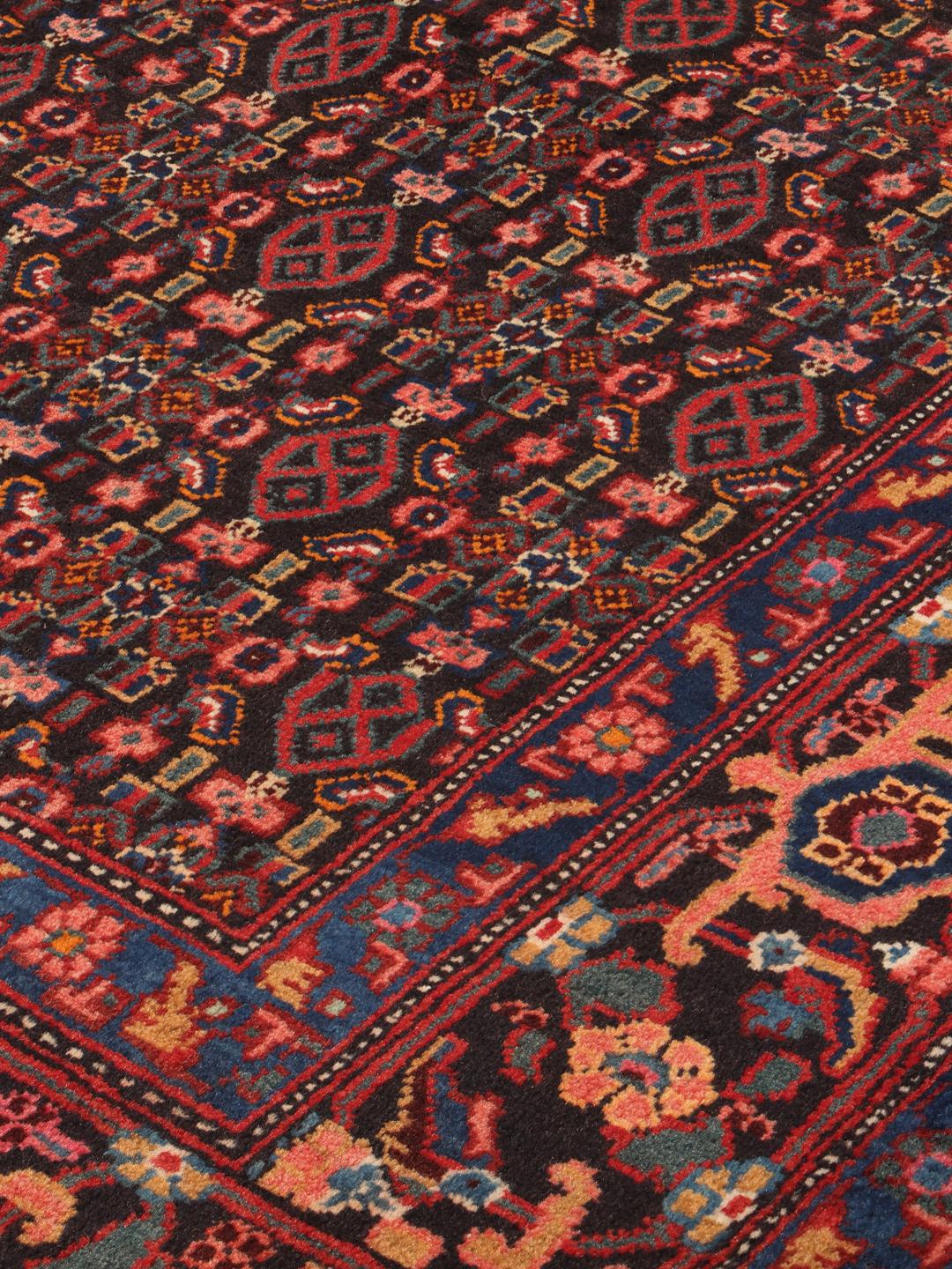 A hand-knotted Senneh rug from the Middle East featuring a dark-red and blue medallion design.