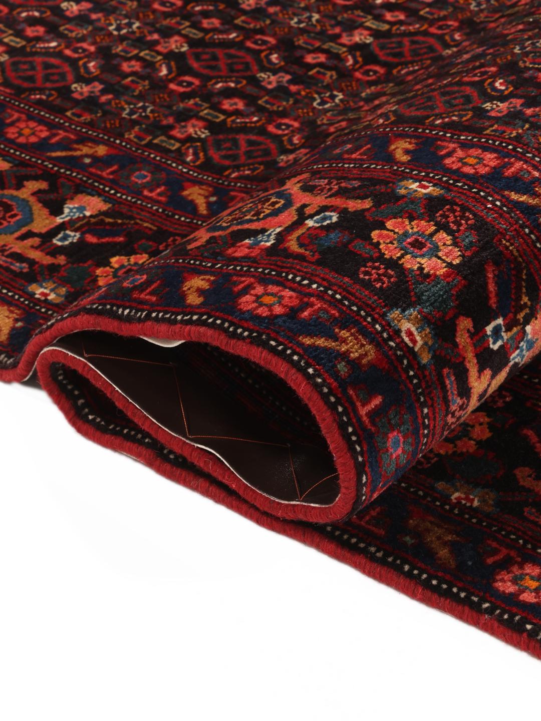 A hand-knotted Senneh rug from the Middle East featuring a dark-red and blue medallion design.