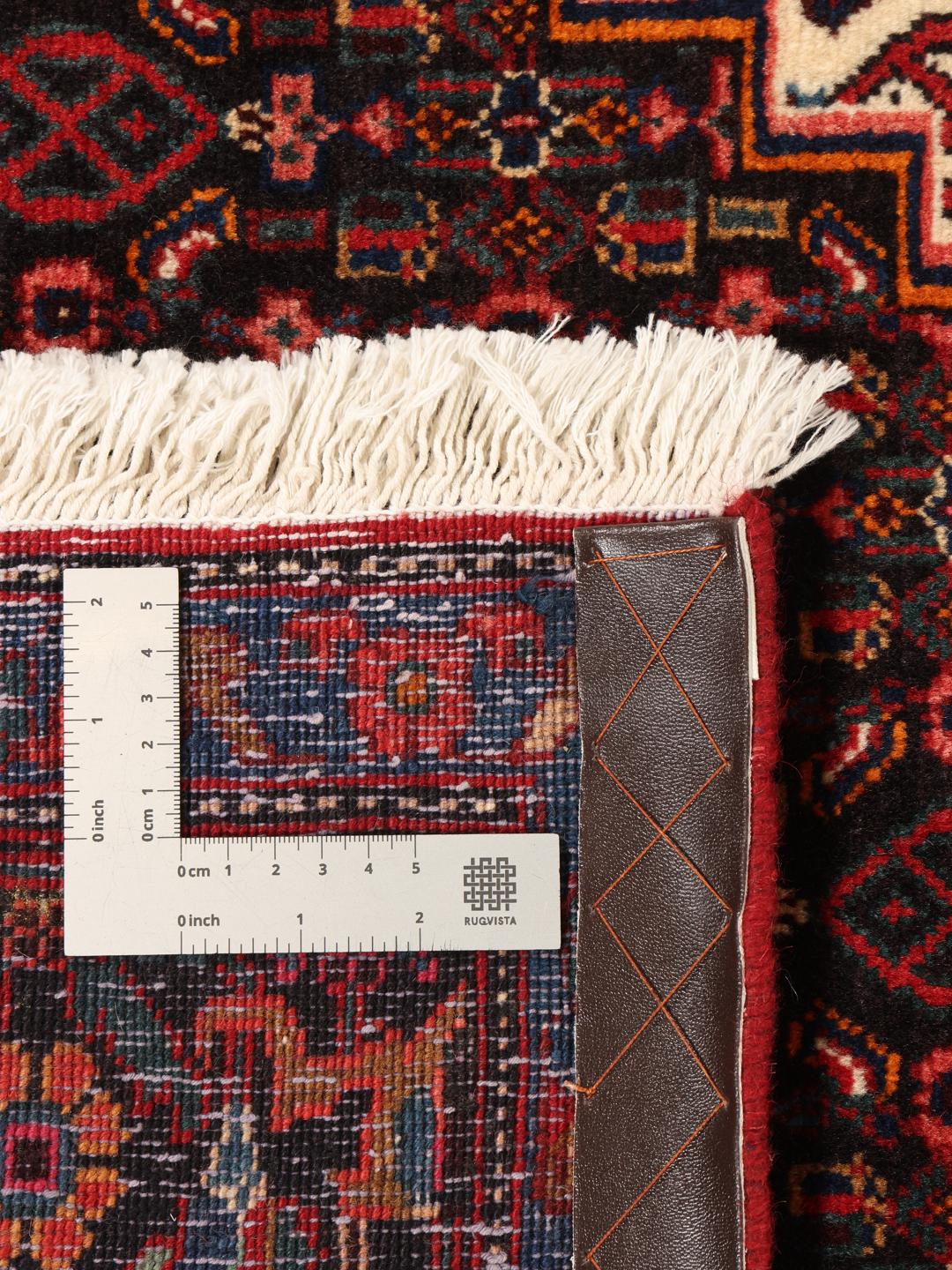 A hand-knotted Senneh rug from the Middle East featuring a dark-red and blue medallion design.