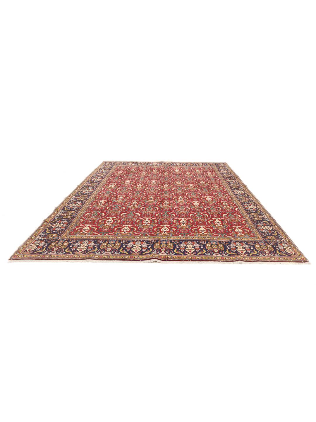 A large rectangular Tabriz rug with a deep red field and intricate floral motifs from the Middle East.