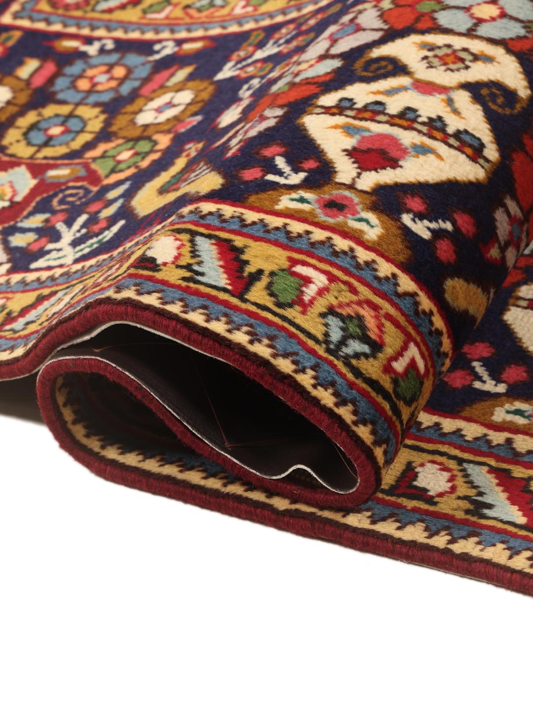 A large rectangular Tabriz rug with a deep red field and intricate floral motifs from the Middle East.