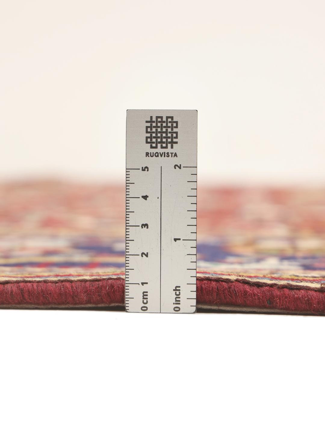 A large rectangular Tabriz rug with a deep red field and intricate floral motifs from the Middle East.