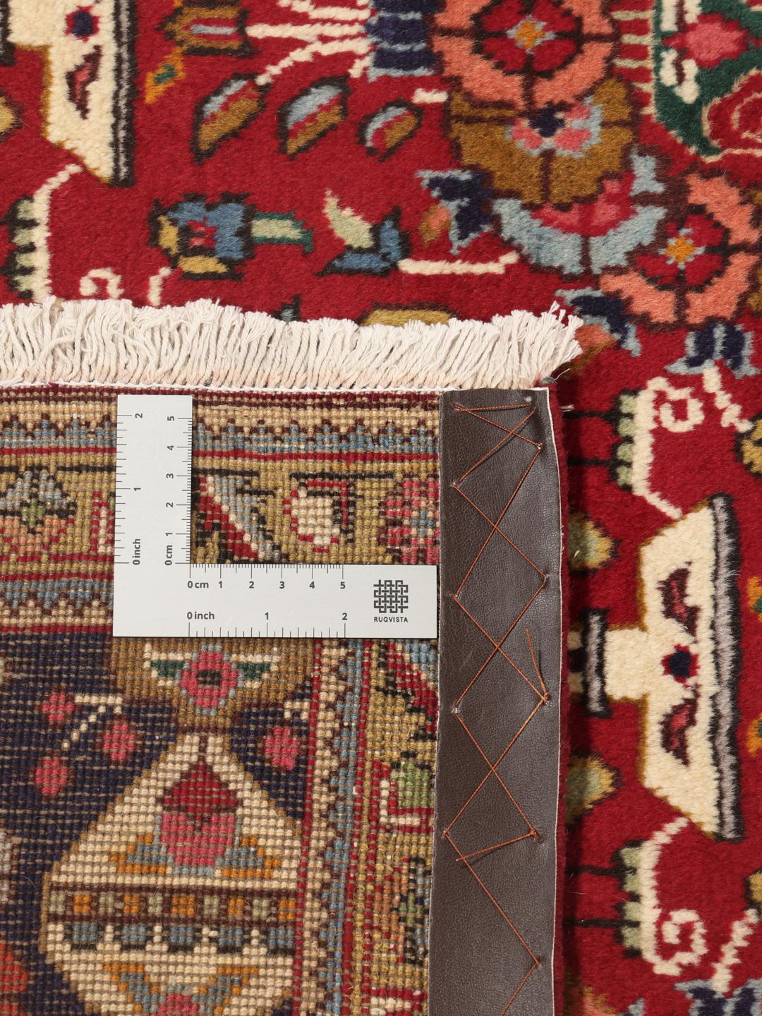 A large rectangular Tabriz rug with a deep red field and intricate floral motifs from the Middle East.