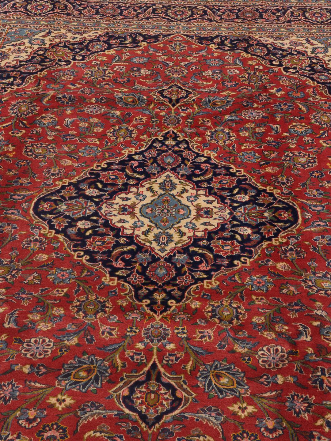 A hand-knotted Keshan rug from the Middle East with a red field and traditional floral motifs.