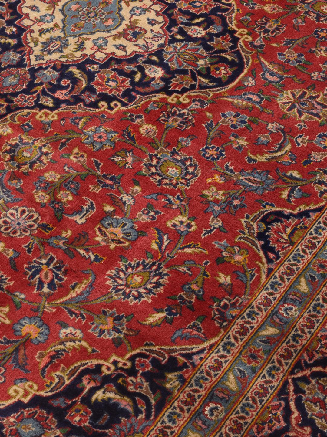 A hand-knotted Keshan rug from the Middle East with a red field and traditional floral motifs.