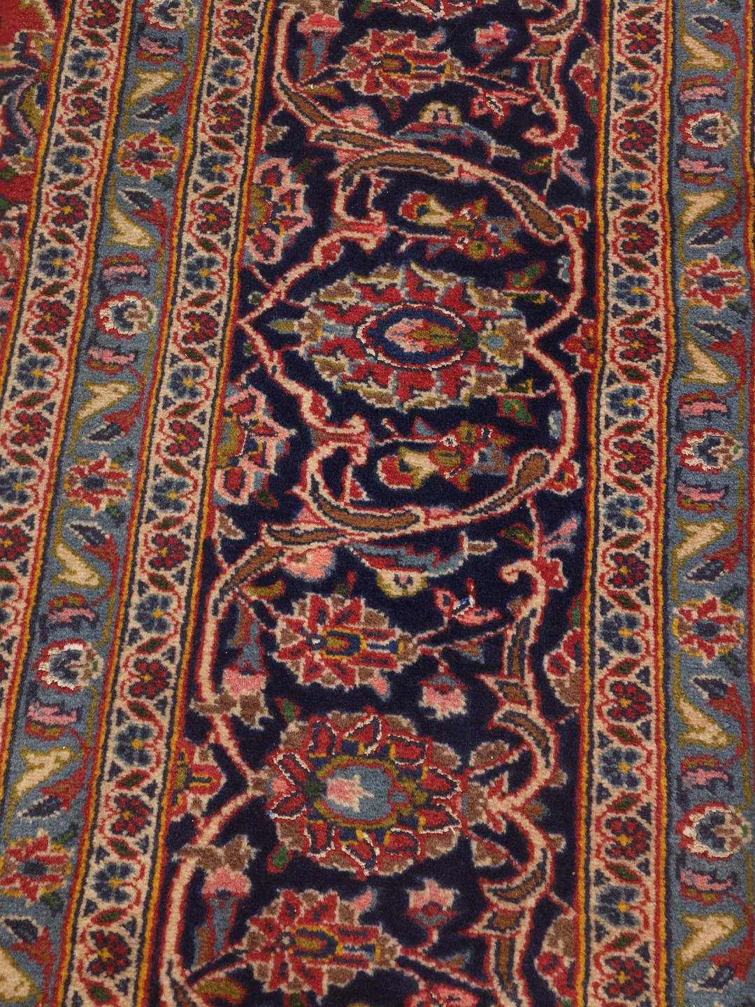 A hand-knotted Keshan rug from the Middle East with a red field and traditional floral motifs.