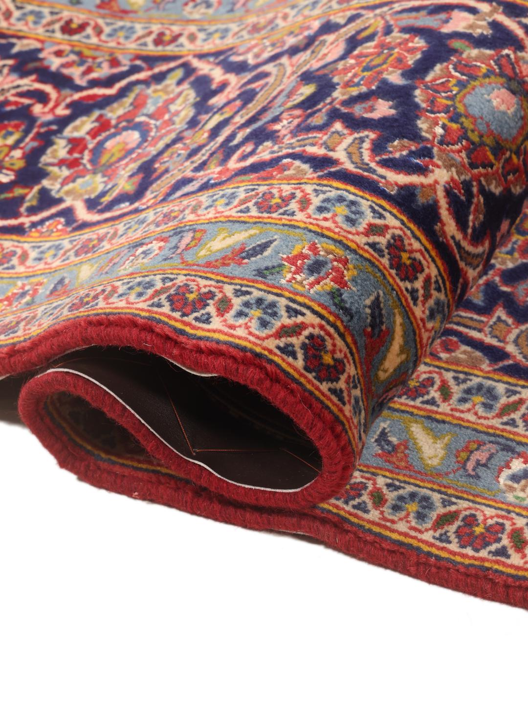 A hand-knotted Keshan rug from the Middle East with a red field and traditional floral motifs.