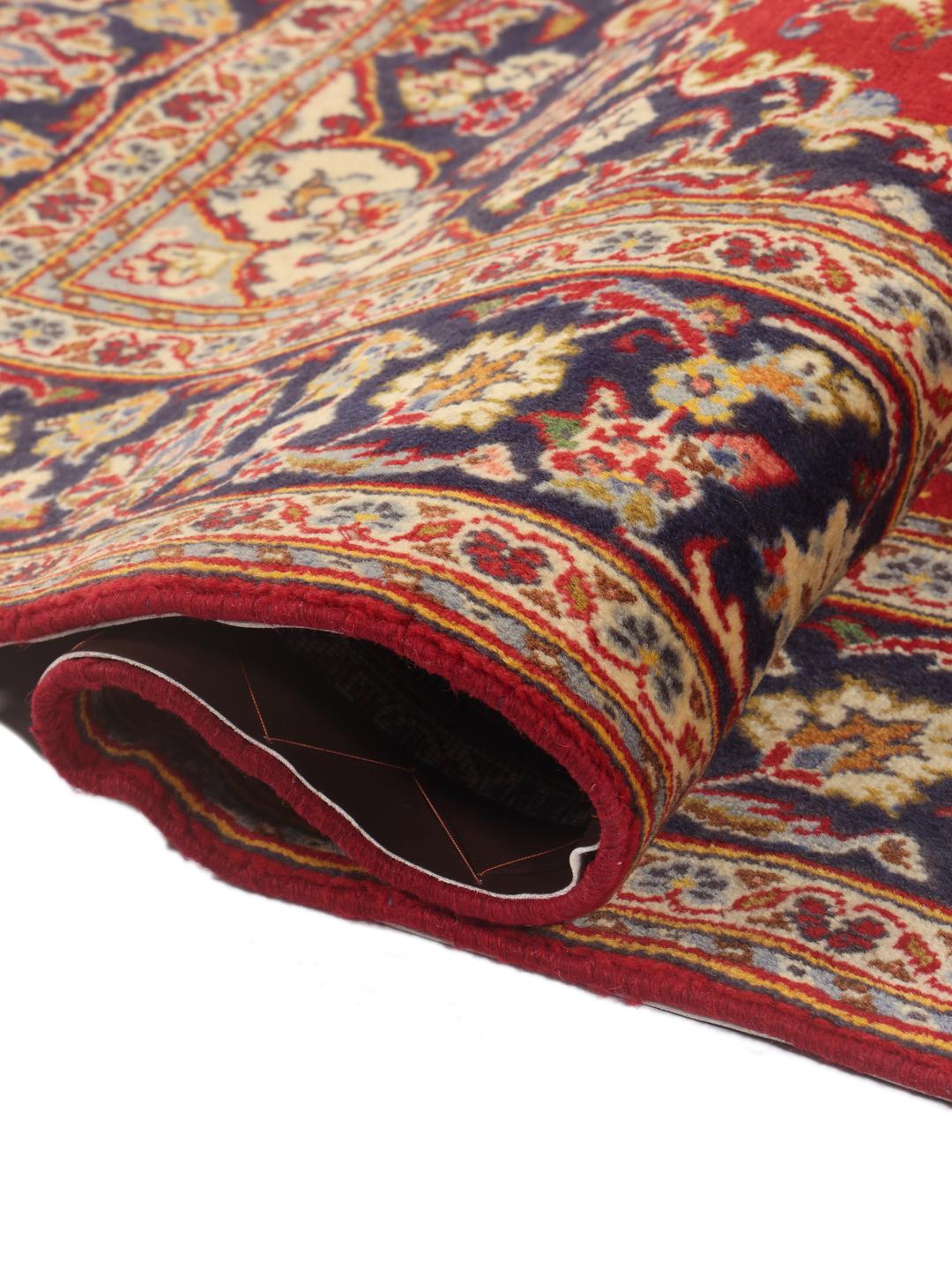 A hand-knotted Middle Eastern Keshan rug with a vibrant red and deep blue floral pattern.