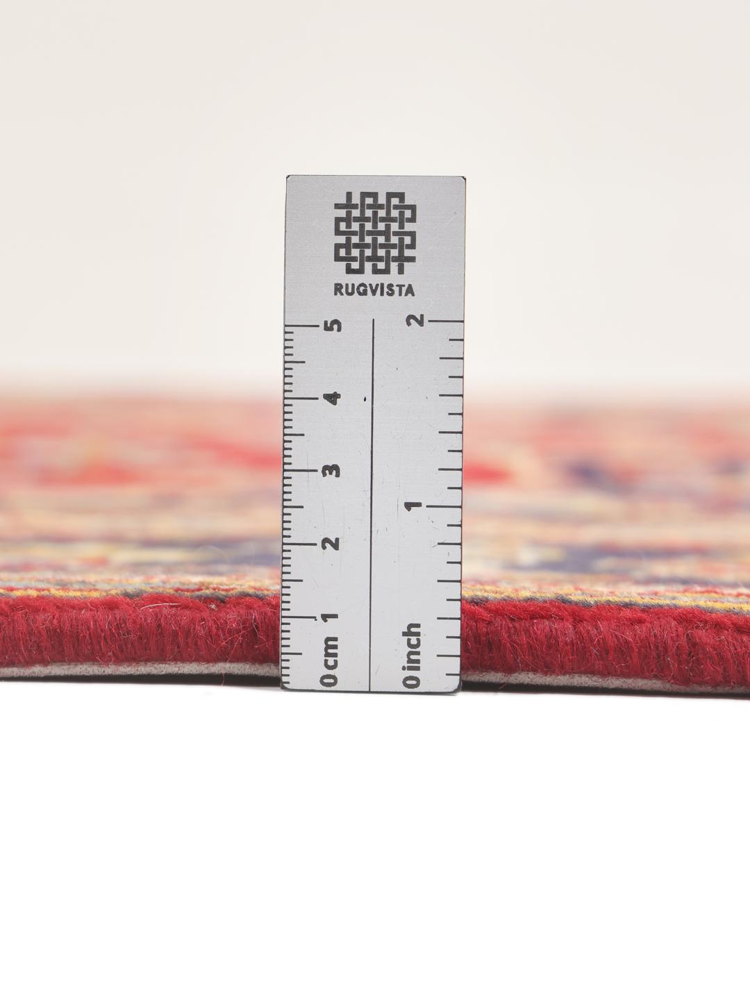 A hand-knotted Middle Eastern Keshan rug with a vibrant red and deep blue floral pattern.