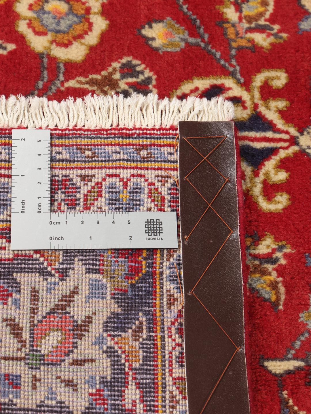 A hand-knotted Middle Eastern Keshan rug with a vibrant red and deep blue floral pattern.