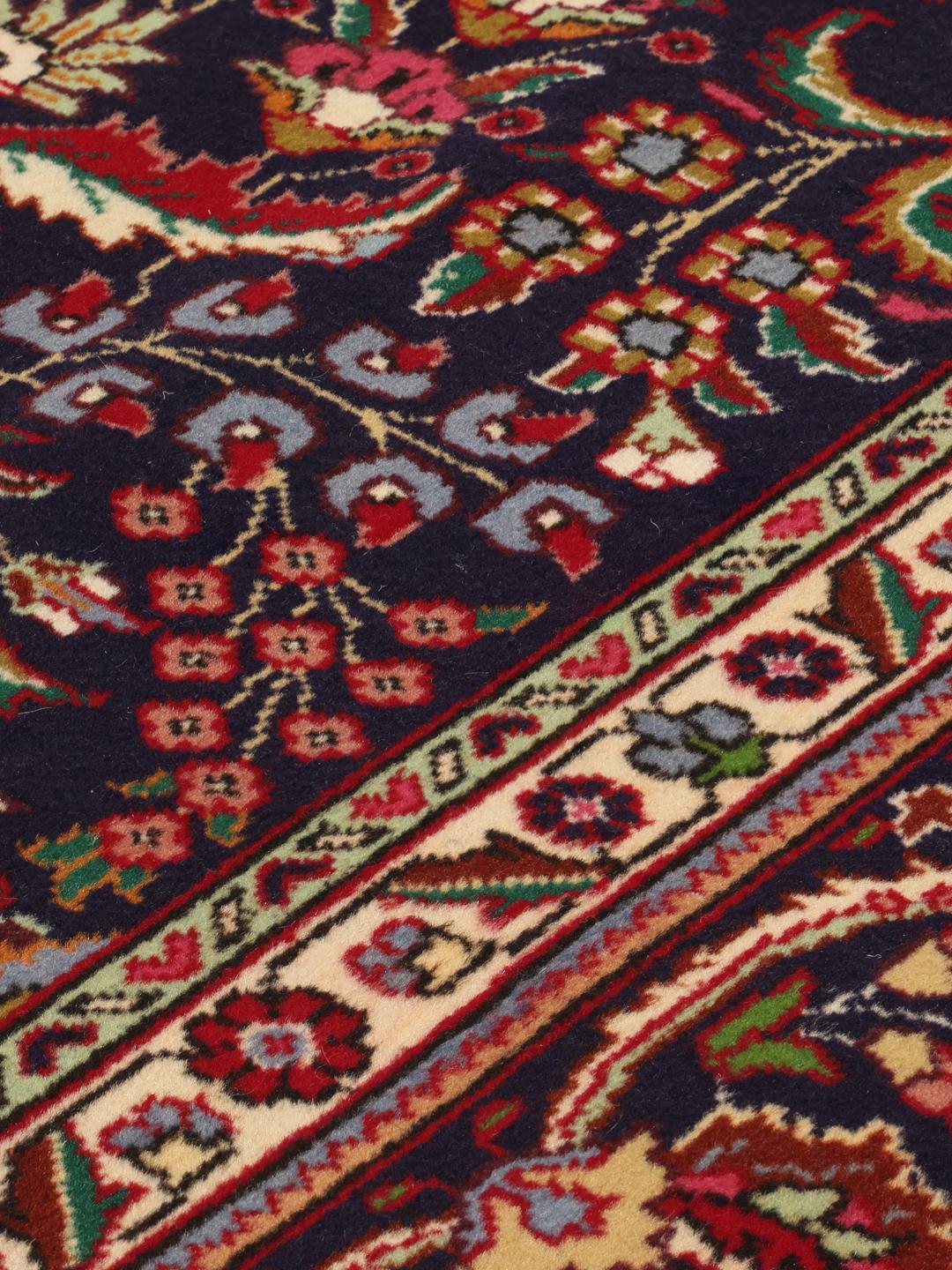 Et håndknyttet Tabriz 40 Raj-tæppe fra Mellemøsten i mørkeblå og røde nuancer.