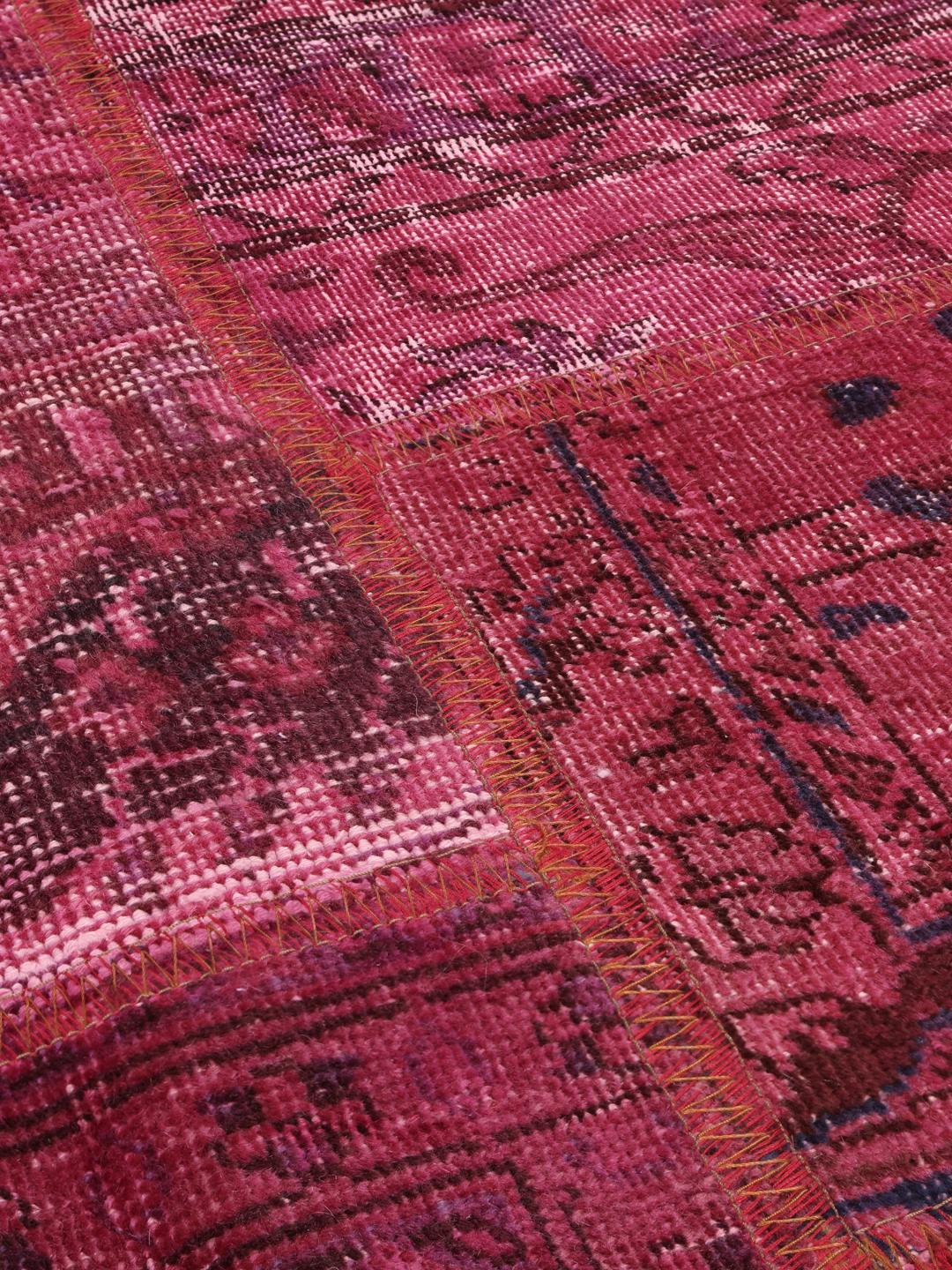 Een levendig roze patchwork tapijt van oorsprong uit het Midden-Oosten met gevarieerde handgeknoopte patronen.