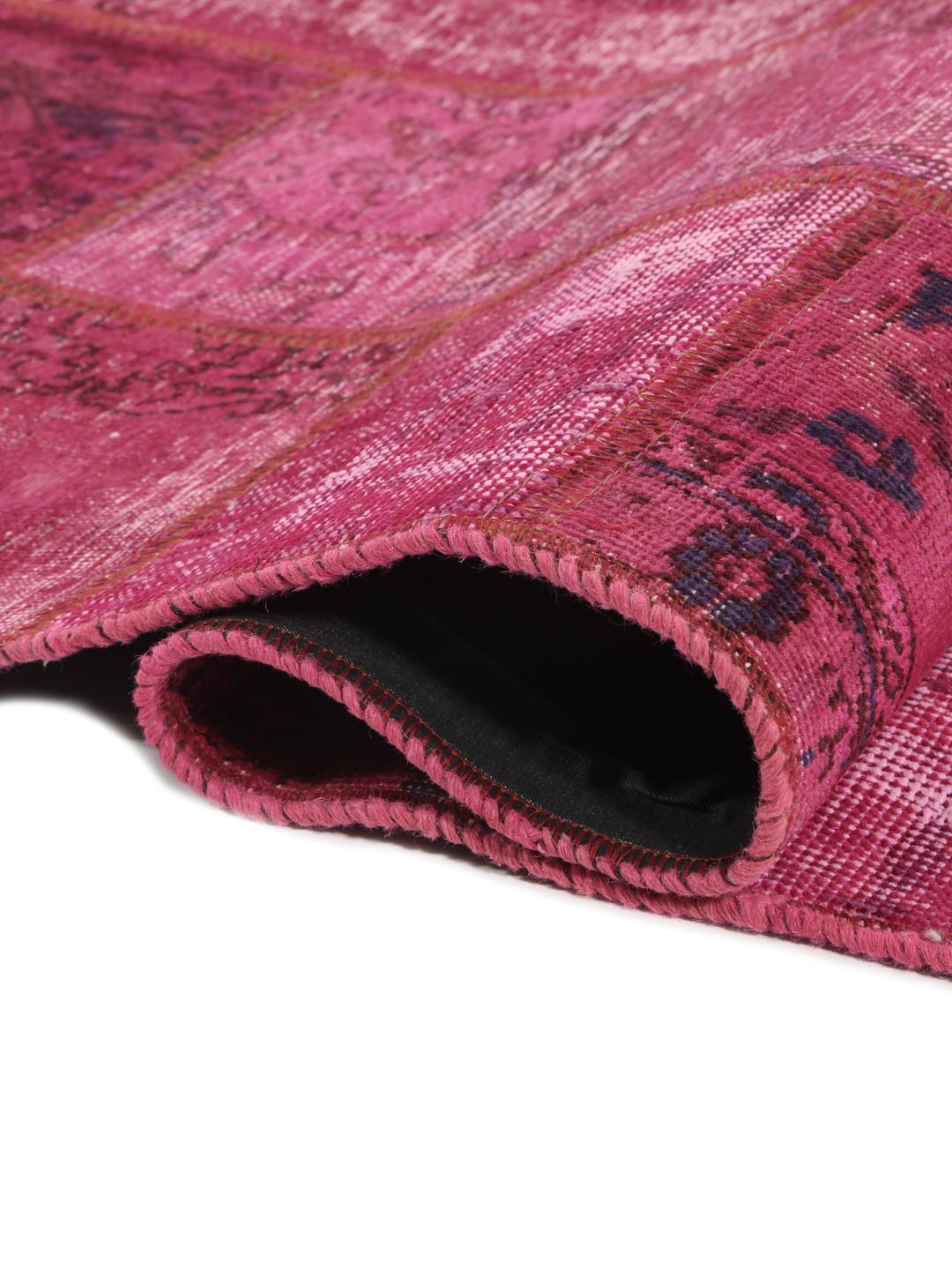 Een levendig roze patchwork tapijt van oorsprong uit het Midden-Oosten met gevarieerde handgeknoopte patronen.