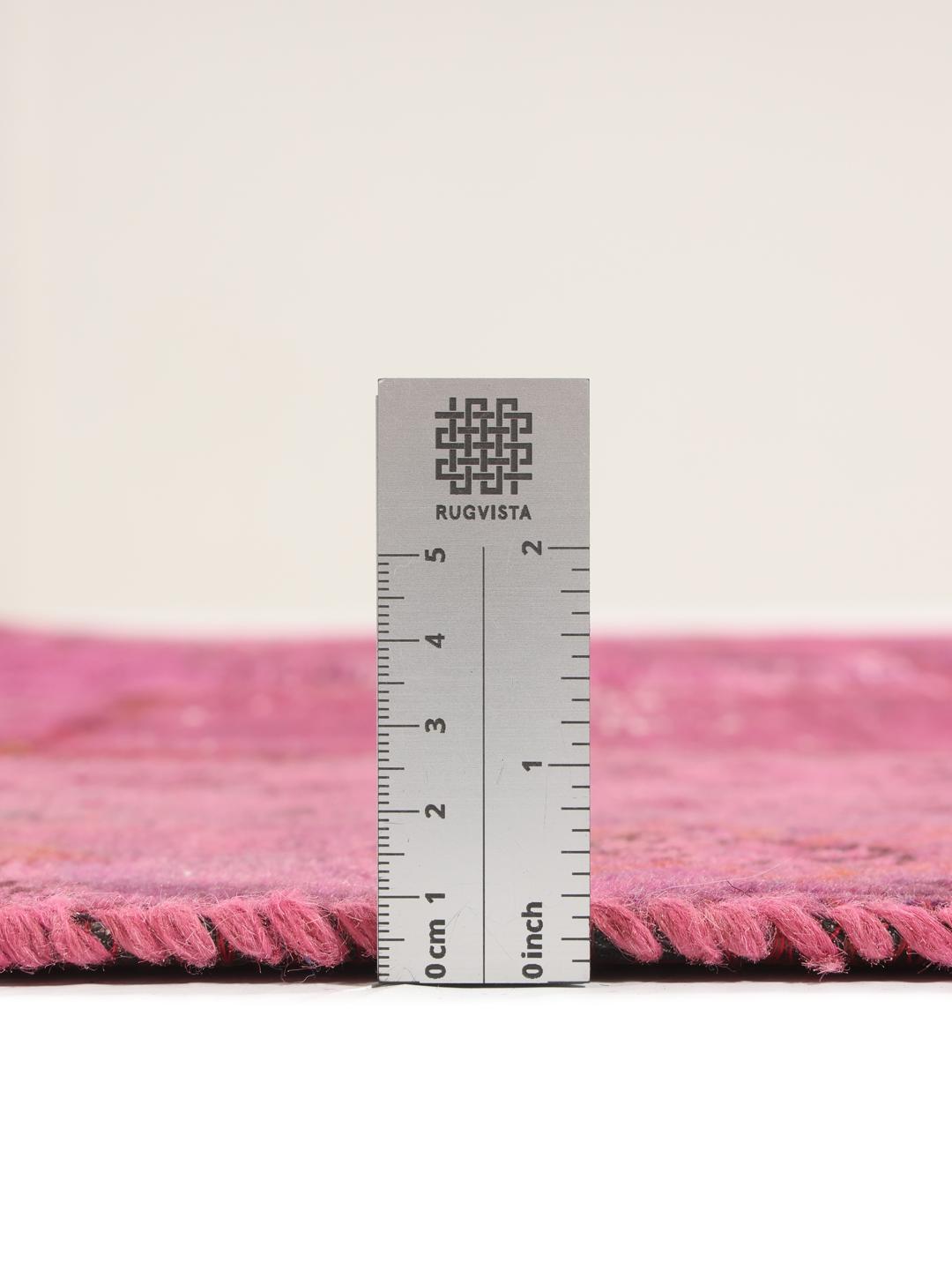 Een levendig roze patchwork tapijt van oorsprong uit het Midden-Oosten met gevarieerde handgeknoopte patronen.