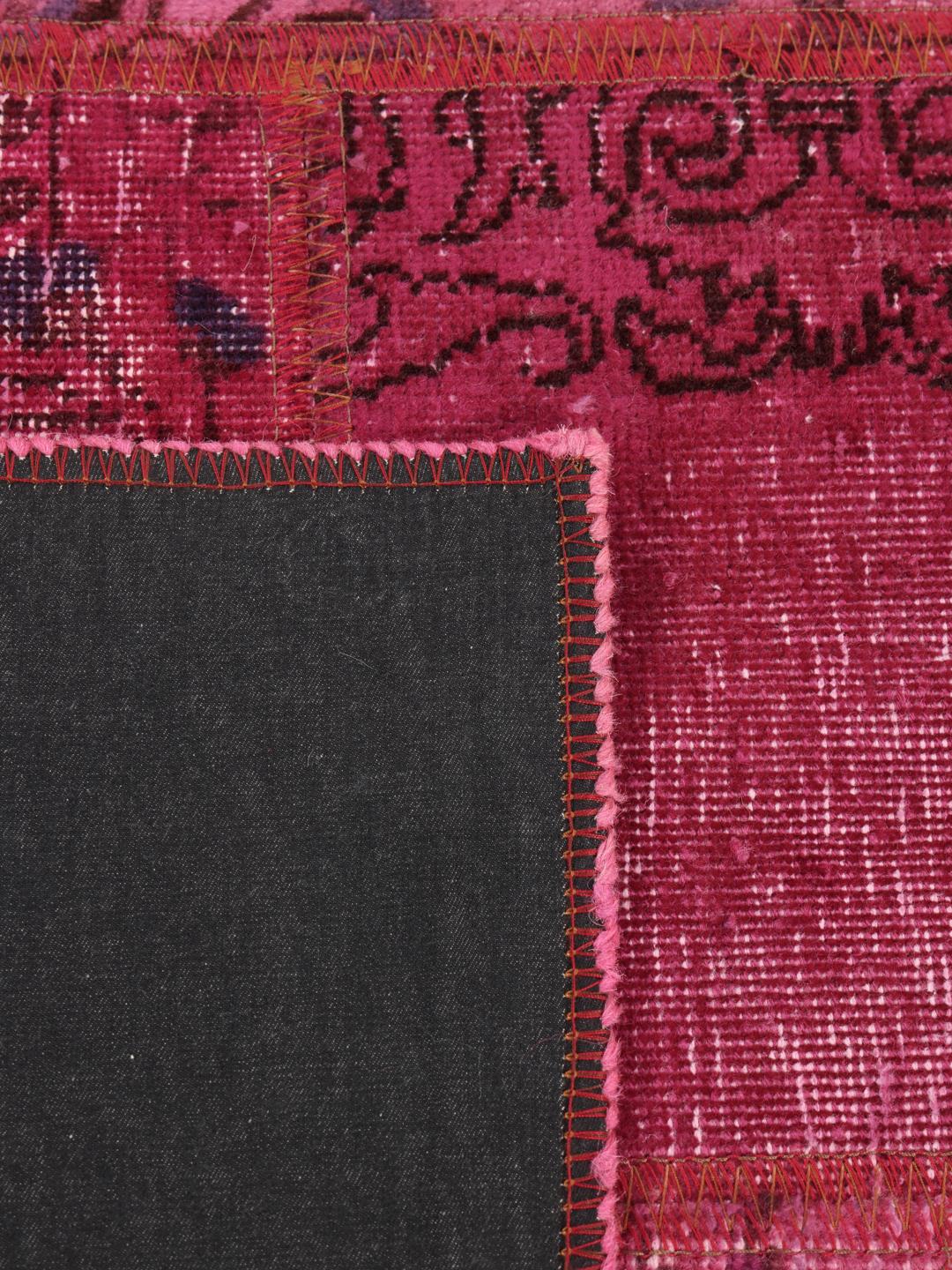 Een levendig roze patchwork tapijt van oorsprong uit het Midden-Oosten met gevarieerde handgeknoopte patronen.