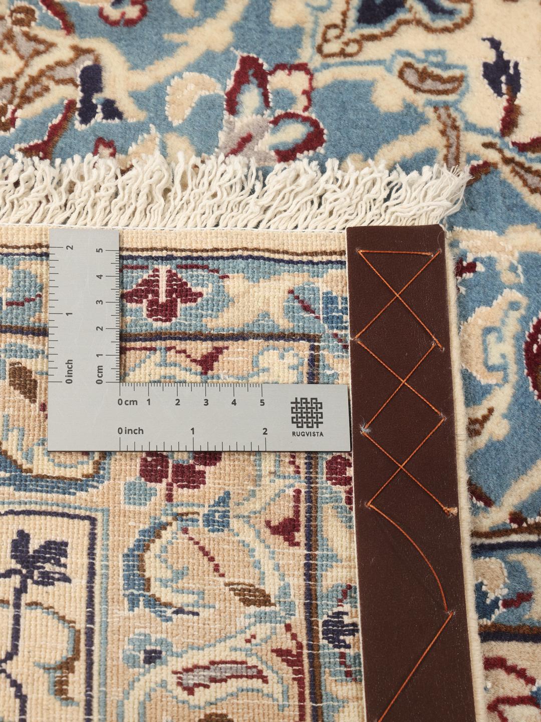 A large, rectangular Nain 9La rug with intricate blue and red floral patterns on a beige field, originating from the Middle East.