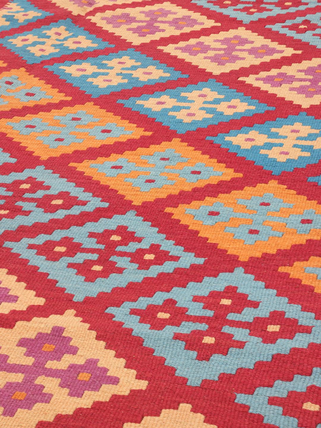 A hand-woven Kelim Ghashghai rug from the Middle East with a vibrant multicolor geometric pattern.