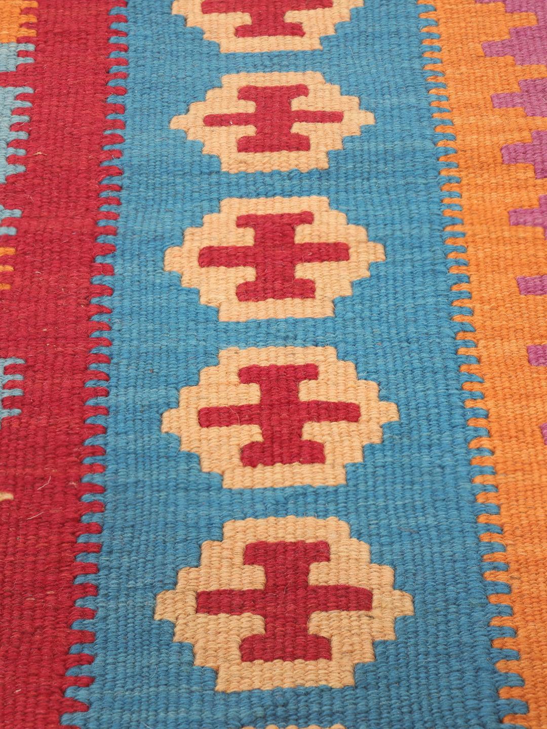 A hand-woven Kelim Ghashghai rug from the Middle East with a vibrant multicolor geometric pattern.