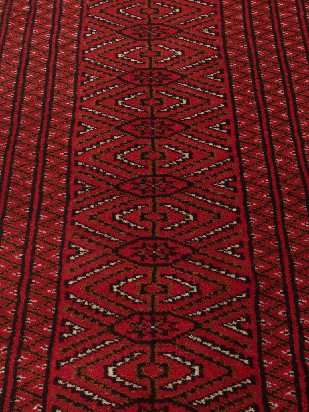 A hand-knotted Turkaman rug from the Middle East in deep red featuring geometric patterns