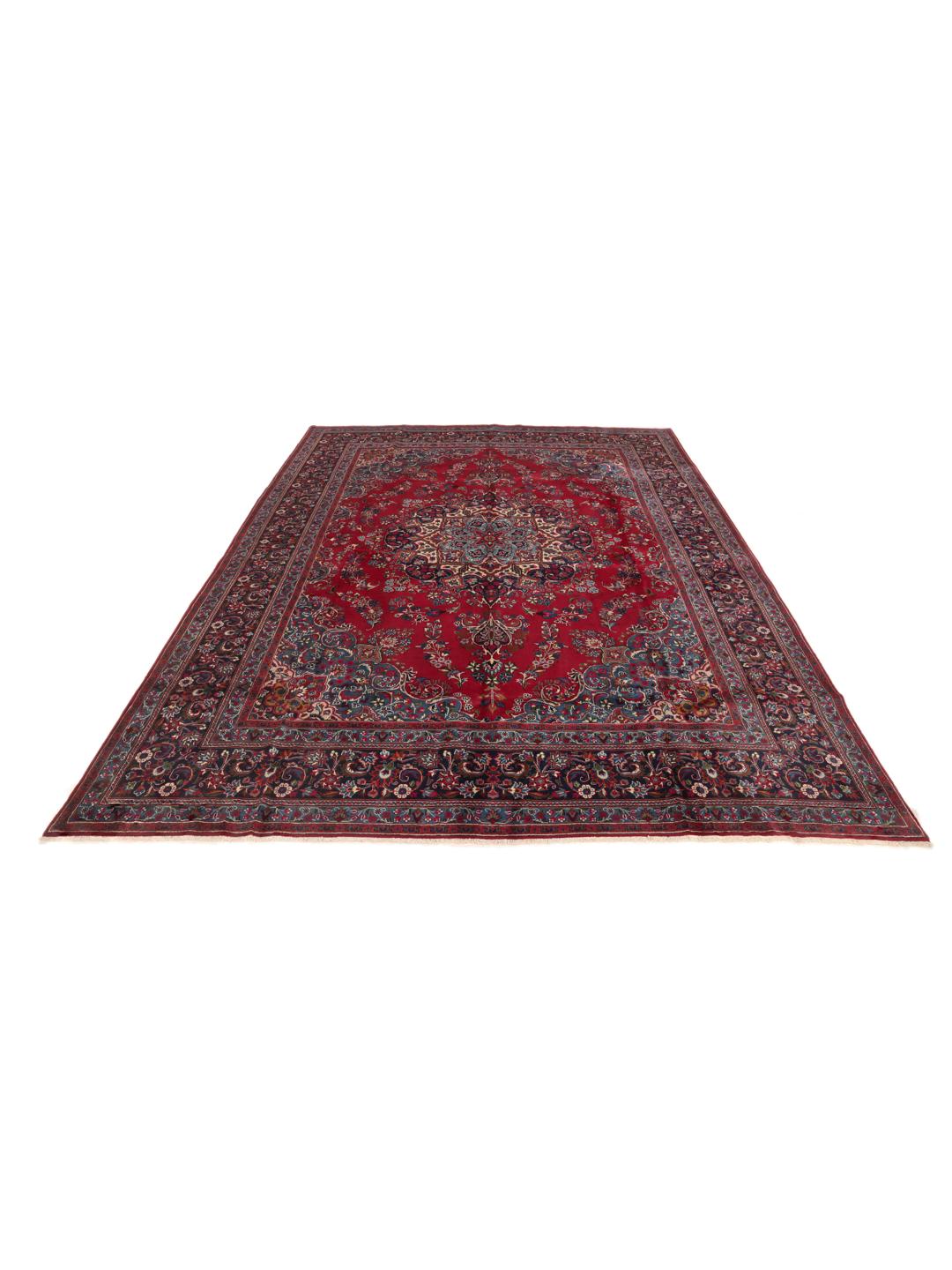 A large, hand-knotted Mashad rug from the Middle East in deep red and blue tones.