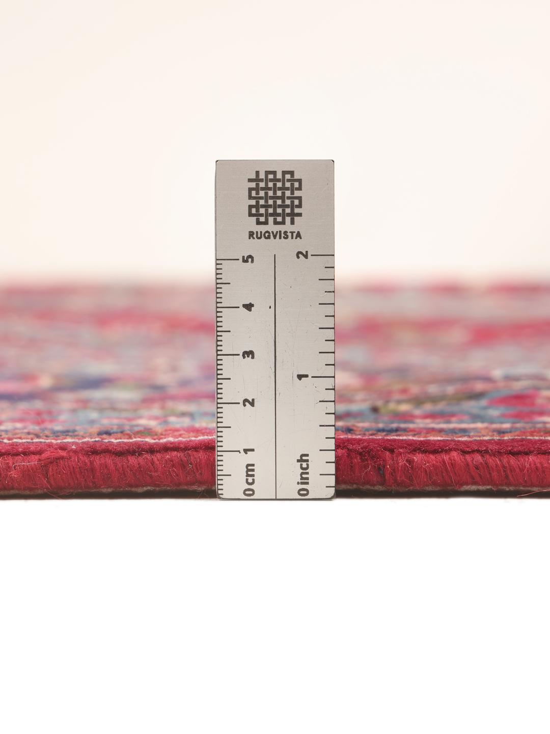 A large, hand-knotted Mashad rug from the Middle East in deep red and blue tones.