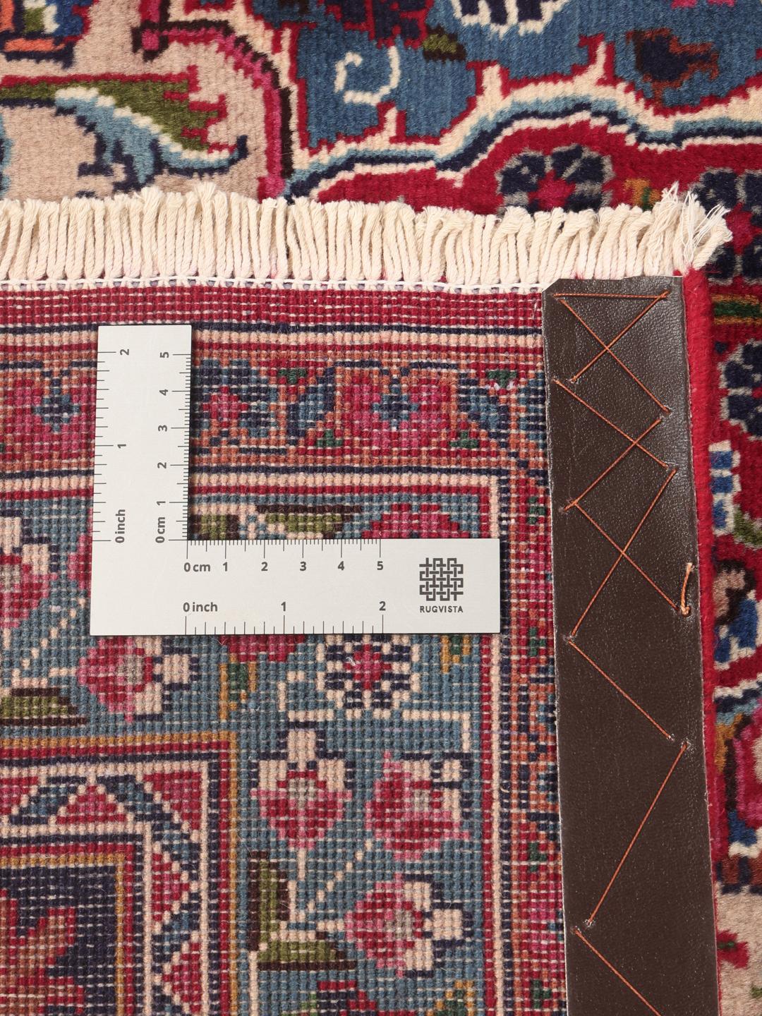A large, hand-knotted Mashad rug from the Middle East in deep red and blue tones.